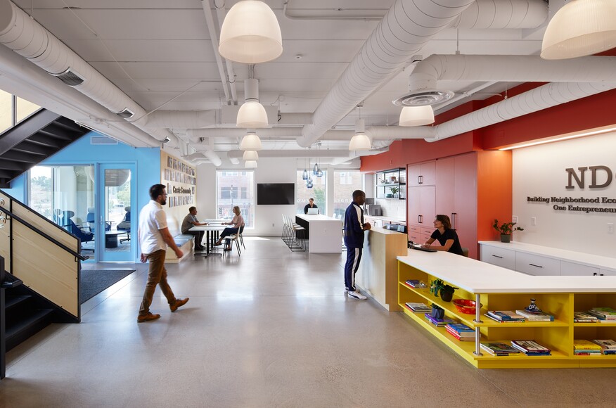 The interior of NDC headquarters; a lobby with tables, chairs, a meeting room, and a front desk.